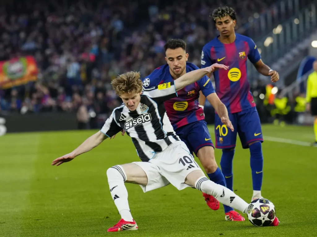 Anthony Gordon protège le ballon face à deux joueurs du FC Barcelona lors d’un match de UEFA Champions League, sous les regards des supporters dans un stade bondé.